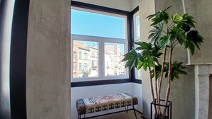 A room with a large window, a bench, and a potted plant.