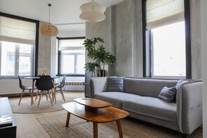 Una sala de estar moderna con un sofá gris, una mesa de centro de madera y un comedor con mesa y sillas.