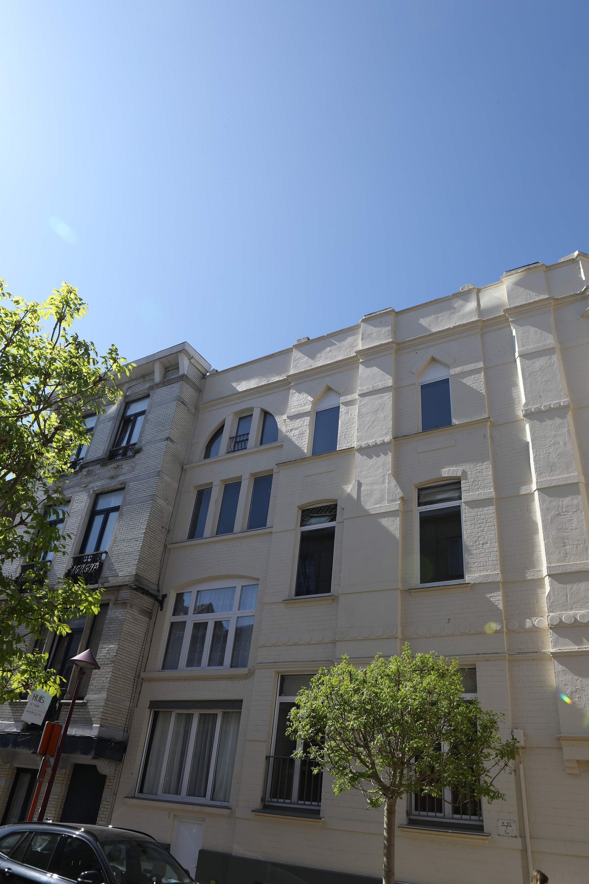 A multi-story building with a classic architectural style, featuring a mix of rectangular and arched windows, and a flat roof.