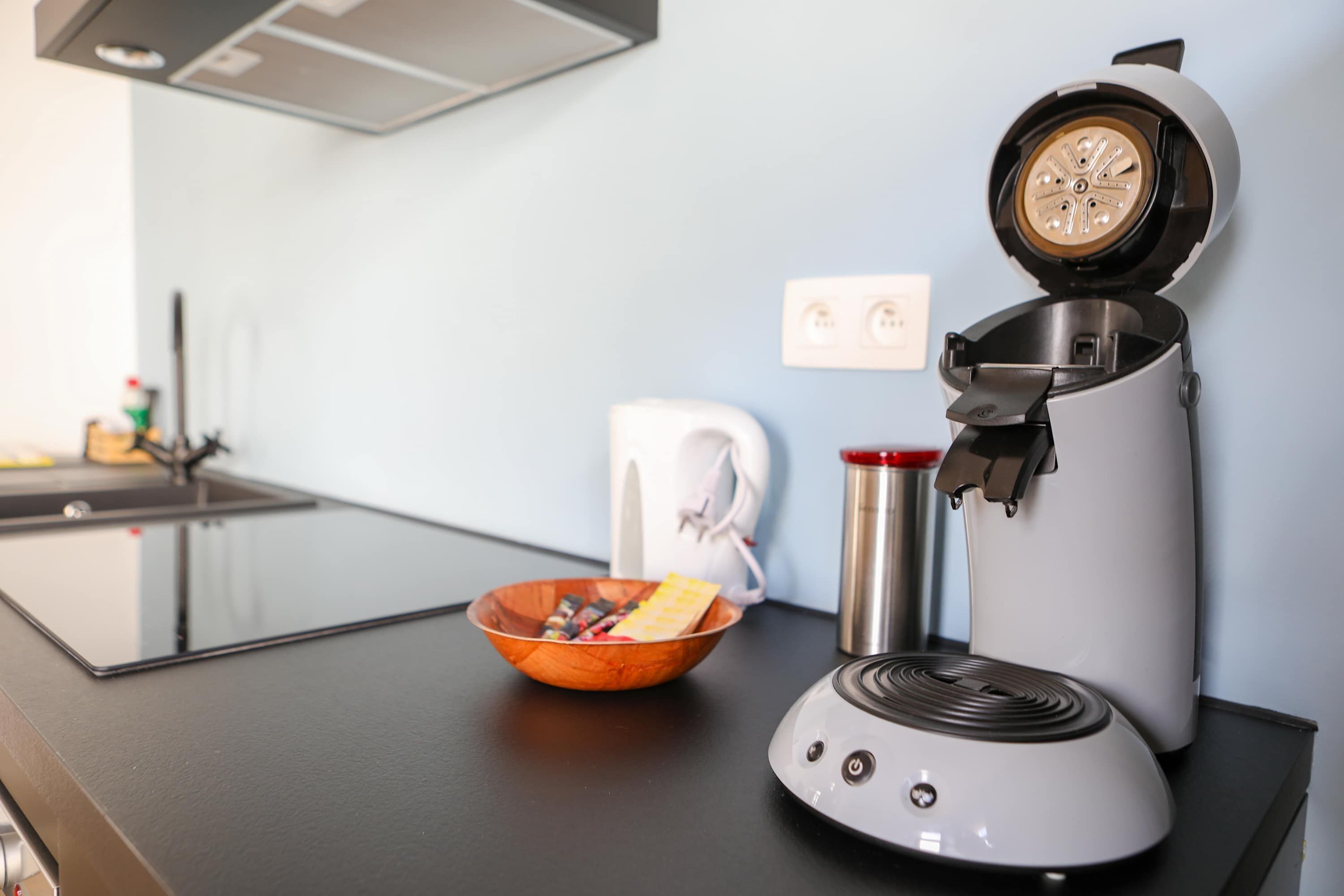 Eine Küche mit Kaffeemaschine, einer Schüssel mit Snacks und einem Wasserkocher auf der Arbeitsplatte.