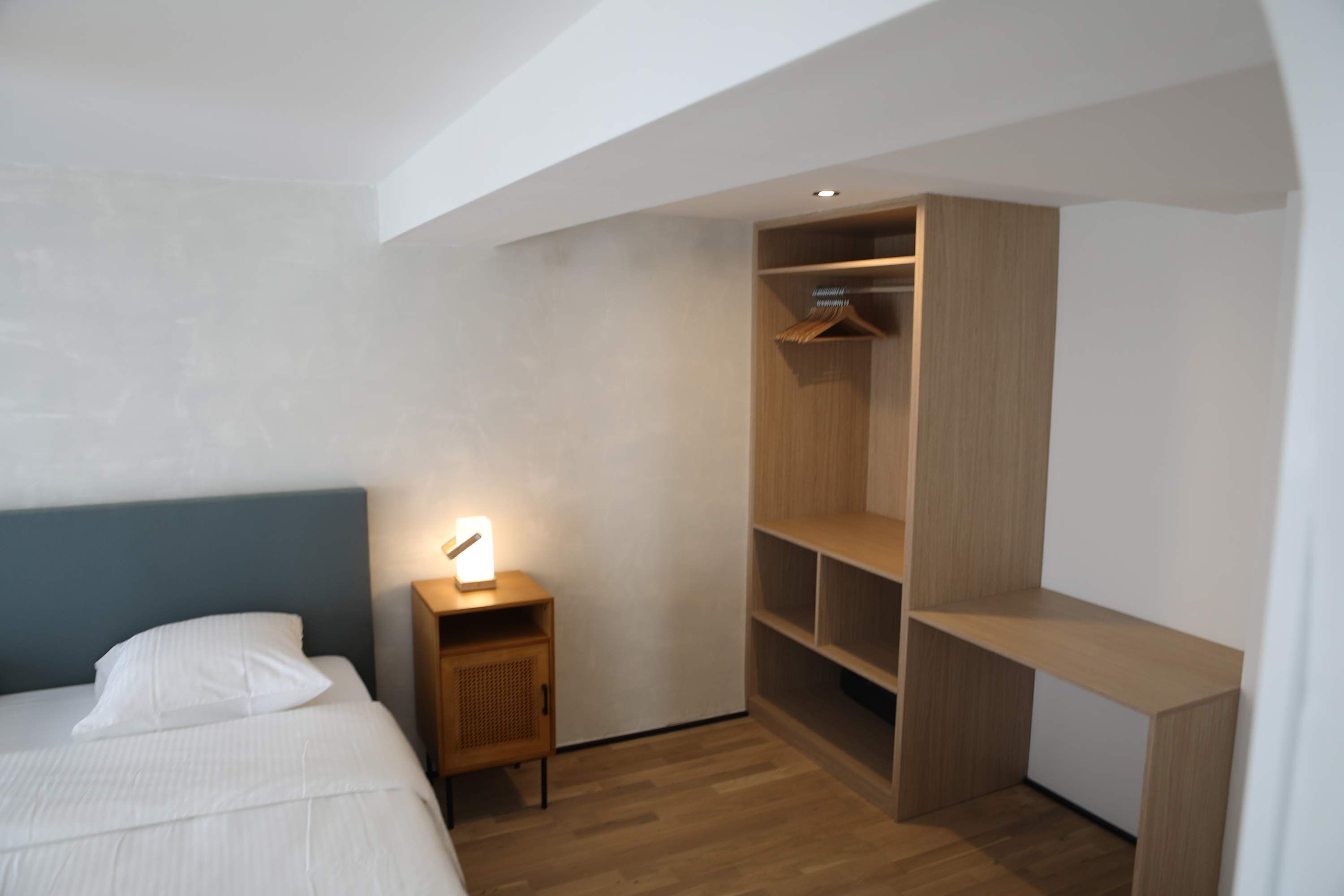 A bedroom with a bed, bedside table, and built-in wooden wardrobe.