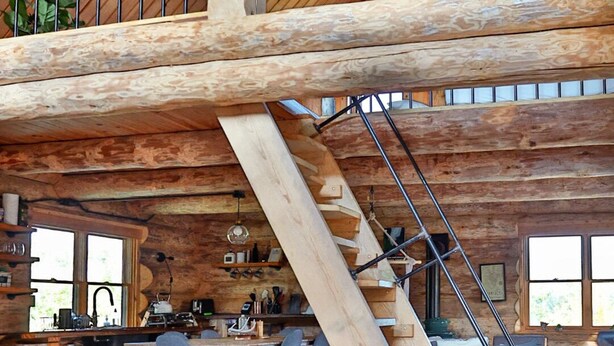 A spacious interior with a high wooden ceiling, a staircase, a kitchen area, and a dining space. - Ely Log Cabin - Off Grid+Solar+WiFi - 40 acres to roam (Ely)