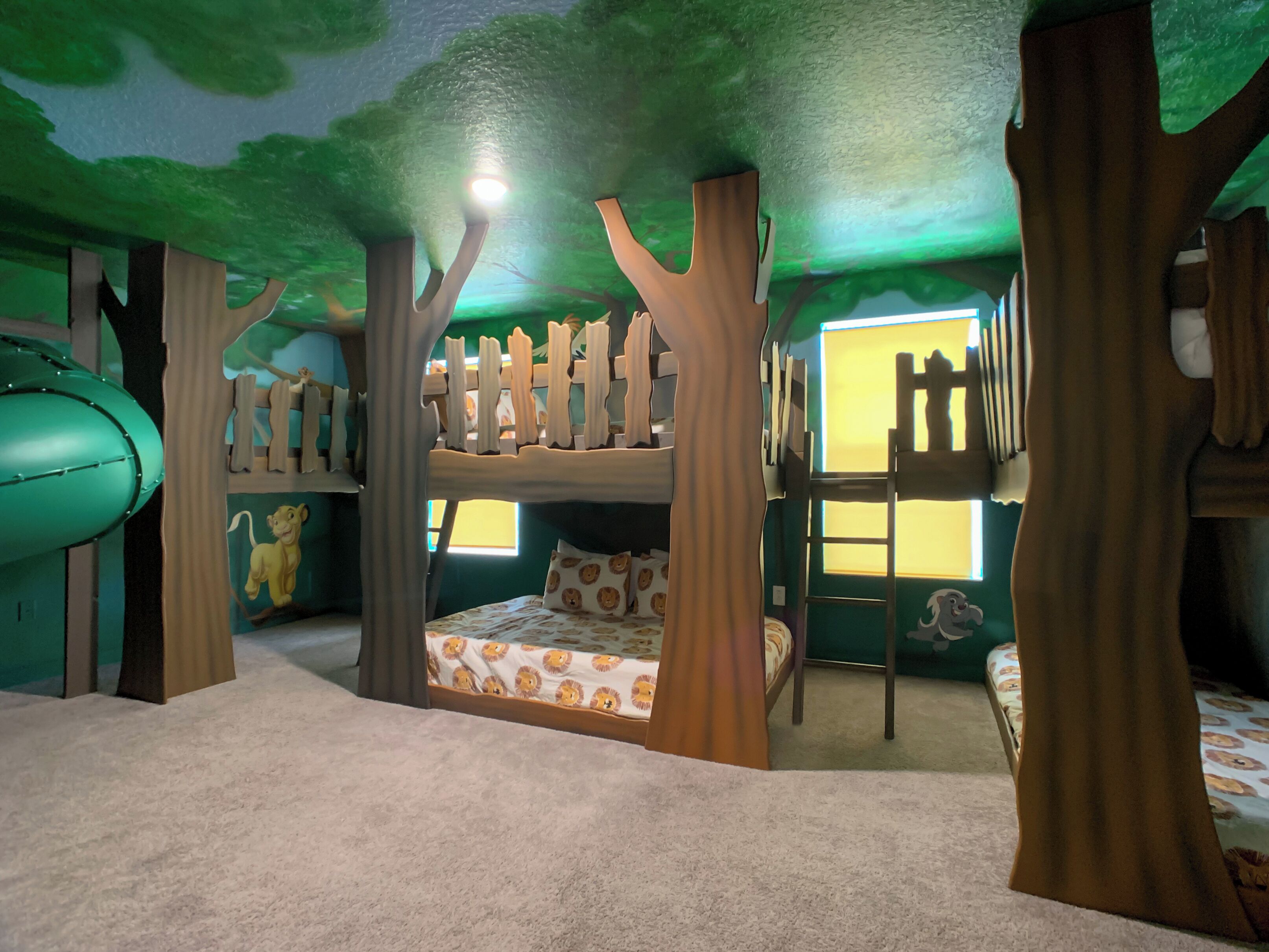 A children's bunk bed with a lion-themed bedspread, surrounded by tree-shaped headboards and a soft carpet.