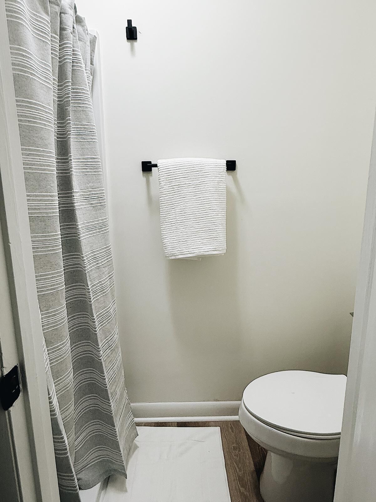 A bathroom with a shower curtain, a towel hanging on a rack, and a toilet.