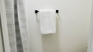 A bathroom with a shower curtain, a towel hanging on a rack, and a toilet.