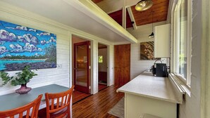 A cozy kitchen with wooden flooring, a dining area with a table and chairs, and a painting on the wall.