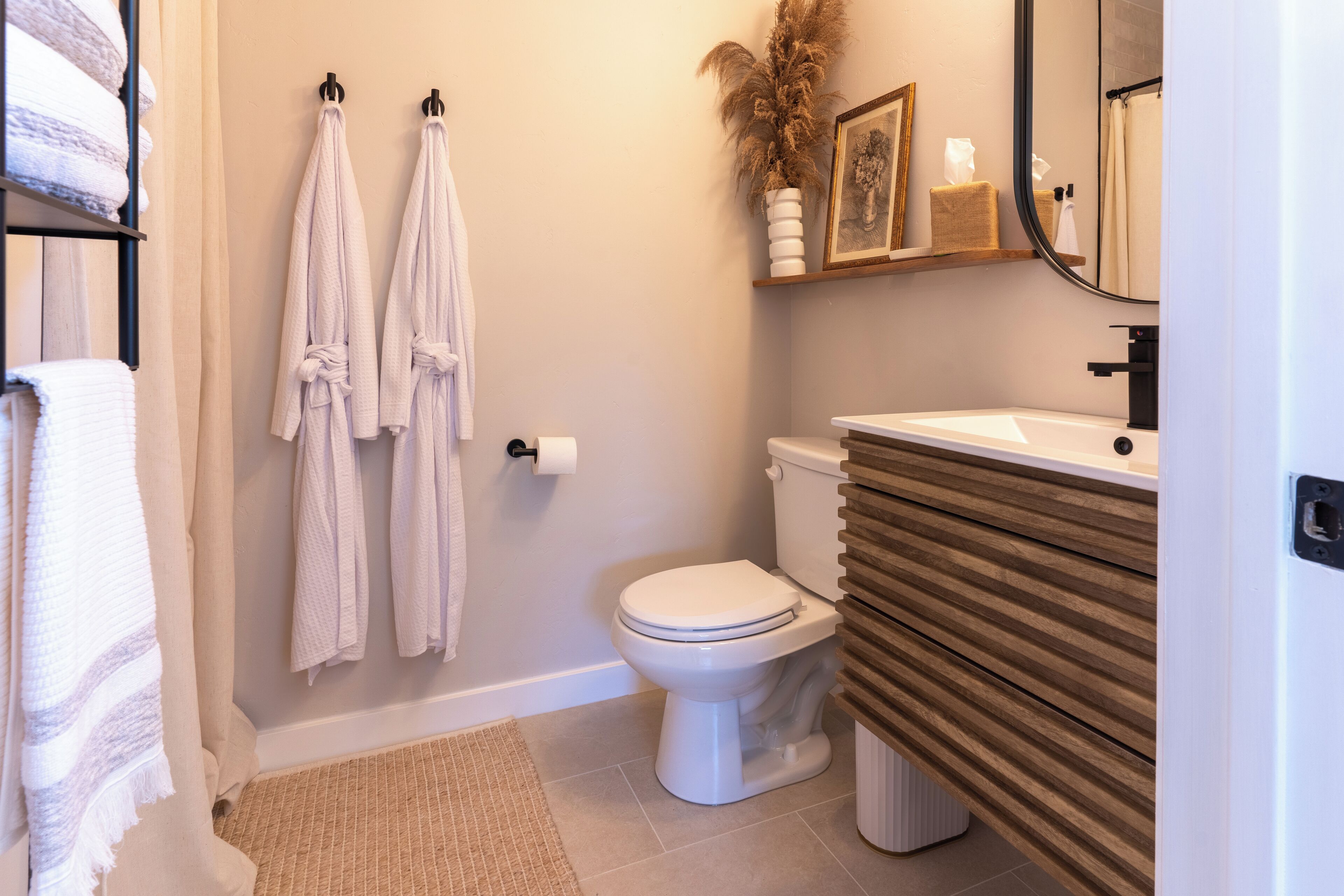 A bathroom with a toilet, a sink, and two towels hanging on hooks.