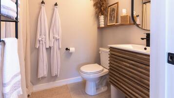 A bathroom with a toilet, a sink, and two towels hanging on hooks.