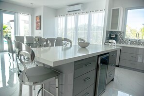 Una cocina moderna con una isla central, sillas de acero inoxidable y vistas al exterior.