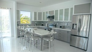 A modern kitchen with a central island, stainless steel appliances, and a view to the outside.