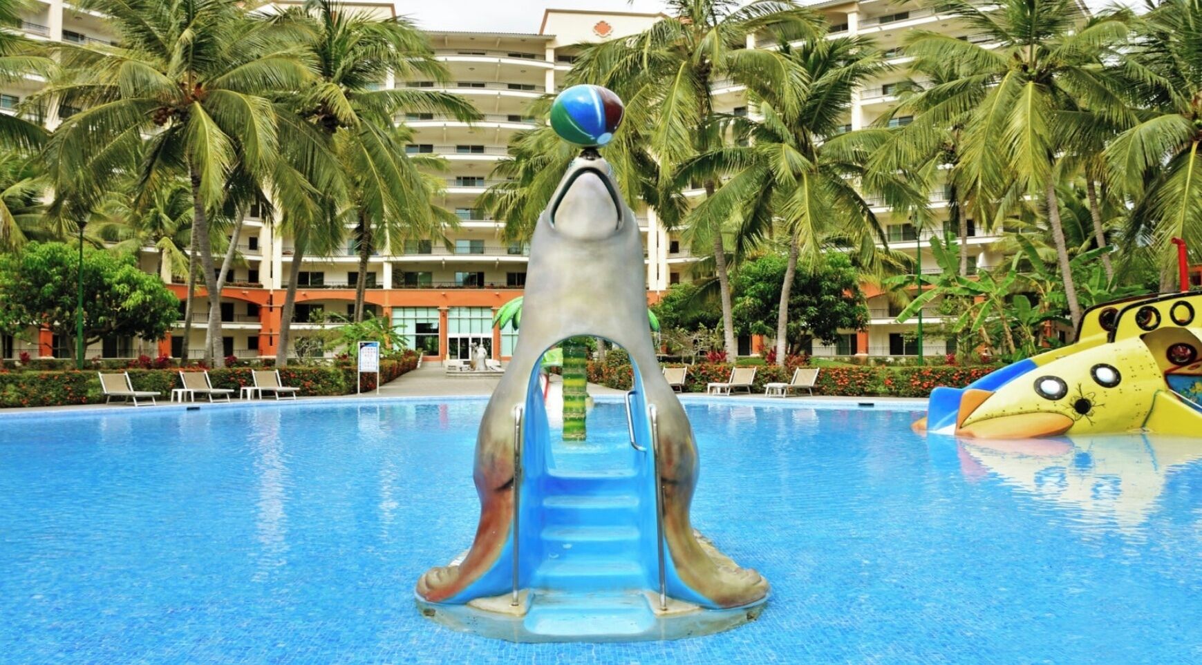 A swimming pool with a dolphin slide and a fish-shaped water feature.