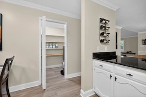 A kitchen with white cabinetry, a black countertop, and a wine rack on the wall. - 3BR Retreat w/ Firepit + Big Garden | Washer/Dryer (Tallahassee)