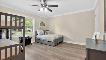 A bedroom with a bunk bed, a single bed, a ceiling fan, and a window with blinds.