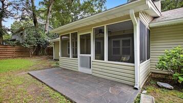 A house with a covered porch, a stone patio, and a fenced backyard.