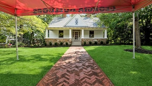 A house with a brick pathway leading to the front door, surrounded by a well-maintained lawn and a stone wall. - Herty House: Walk to UGA & 5 Points (Upper Level) (Athens)