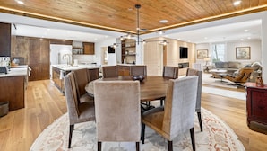 A modern kitchen with wooden cabinets, a dining area with a round table and chairs, and a living room with a sofa and coffee table. - Herty House: Walk to UGA & 5 Points (Upper Level) (Athens)