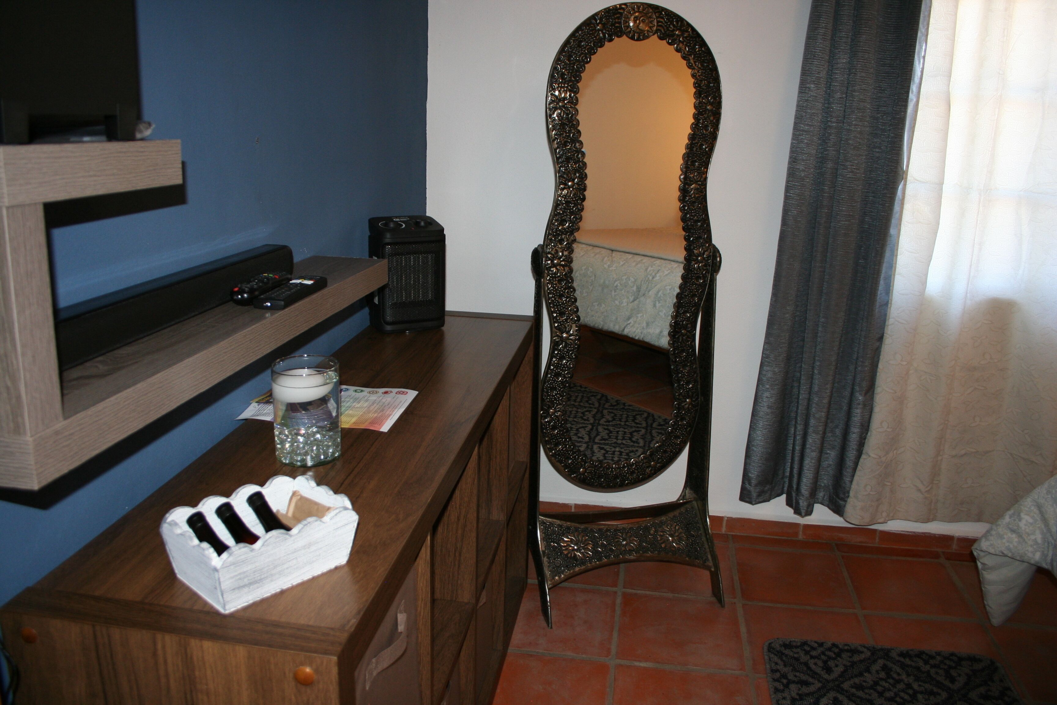 Une pièce comprenant une commode en bois, un miroir, une télécommande, une bougie et un petit objet décoratif.