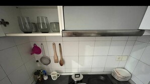 Een keuken met witte kasten, een fornuis, een spoelbak en verschillende keukengerei.