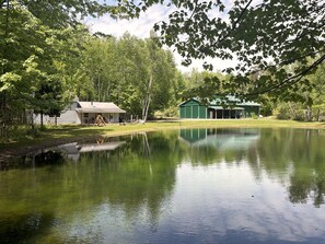 A tranquil lakeside property with a house, a green building, and a swing set.
