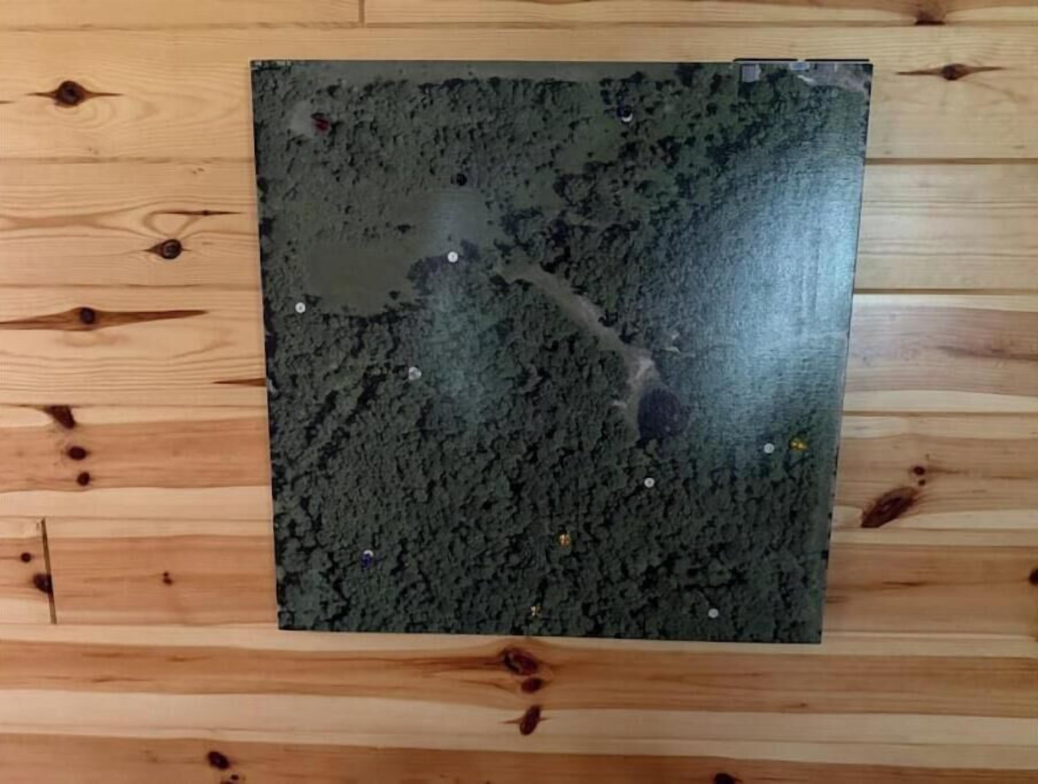 A wooden floor with a dark, textured mat placed on it.