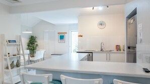 A modern kitchen with a central island, white cabinetry, and a clock on the wall.