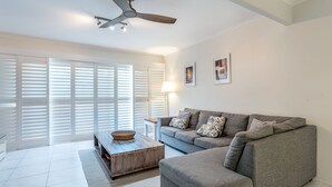 A living room with a grey sofa, a wooden coffee table, and a ceiling fan.