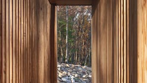 A wooden corridor with a view of a forest and rocks. - The Ridge at Serà - Modern Retreat w/Sauna (Wardensville)