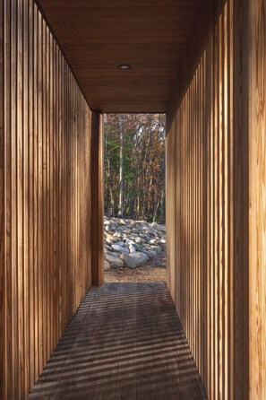 A wooden corridor with a view of a forest and rocks.