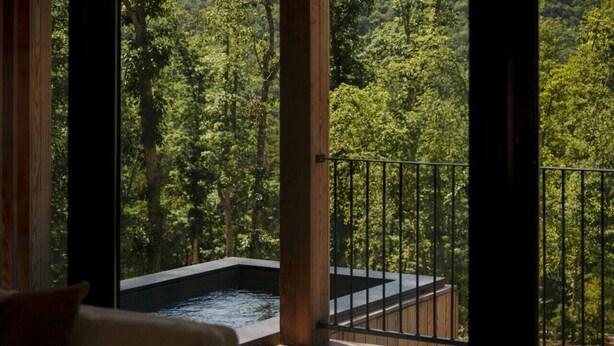 A hot tub on a balcony with a forest view. - The Ridge at Serà - Modern Retreat w/Sauna (Wardensville)