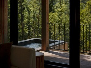 Un jacuzzi sur un balcon avec vue sur la forêt.