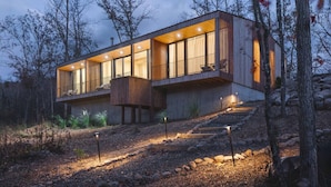 Een modern huis met grote ramen, een balkon en een houten terras.