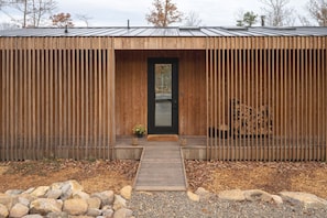 A wooden cabin with a metal roof, a front door, and a small porch area. - The Ridge at Serà - Modern Retreat w/Sauna (Wardensville)