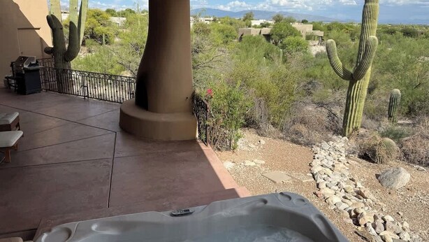 Un espace patio doté d’un jacuzzi, de mobilier d’extérieur et offrant une vue sur des cactus et un paysage désertique.