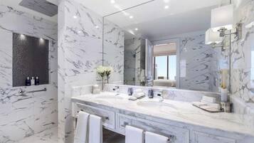 A modern bathroom with marble walls and a large mirror.