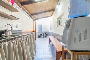 Una cocina con salpicadero de azulejos, un banco de madera, una parrilla y una zona de comedor con taburetes.