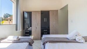 Habitación de hotel con dos camas, un armario y una ventana con cortinas.