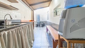 Una cocina con salpicadero de azulejos, un banco de madera, una parrilla y una zona de comedor con taburetes.