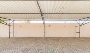 A covered parking area with numbered sections, a metal roof, and a paved floor.