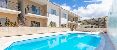 A swimming pool with a clear blue water surface, surrounded by a tiled deck.