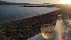 A beach with a table set for a meal, featuring a bottle and a glass labeled "MATTEI". - The Maristella and Argentu villas for large families close to the sea (Aregno)