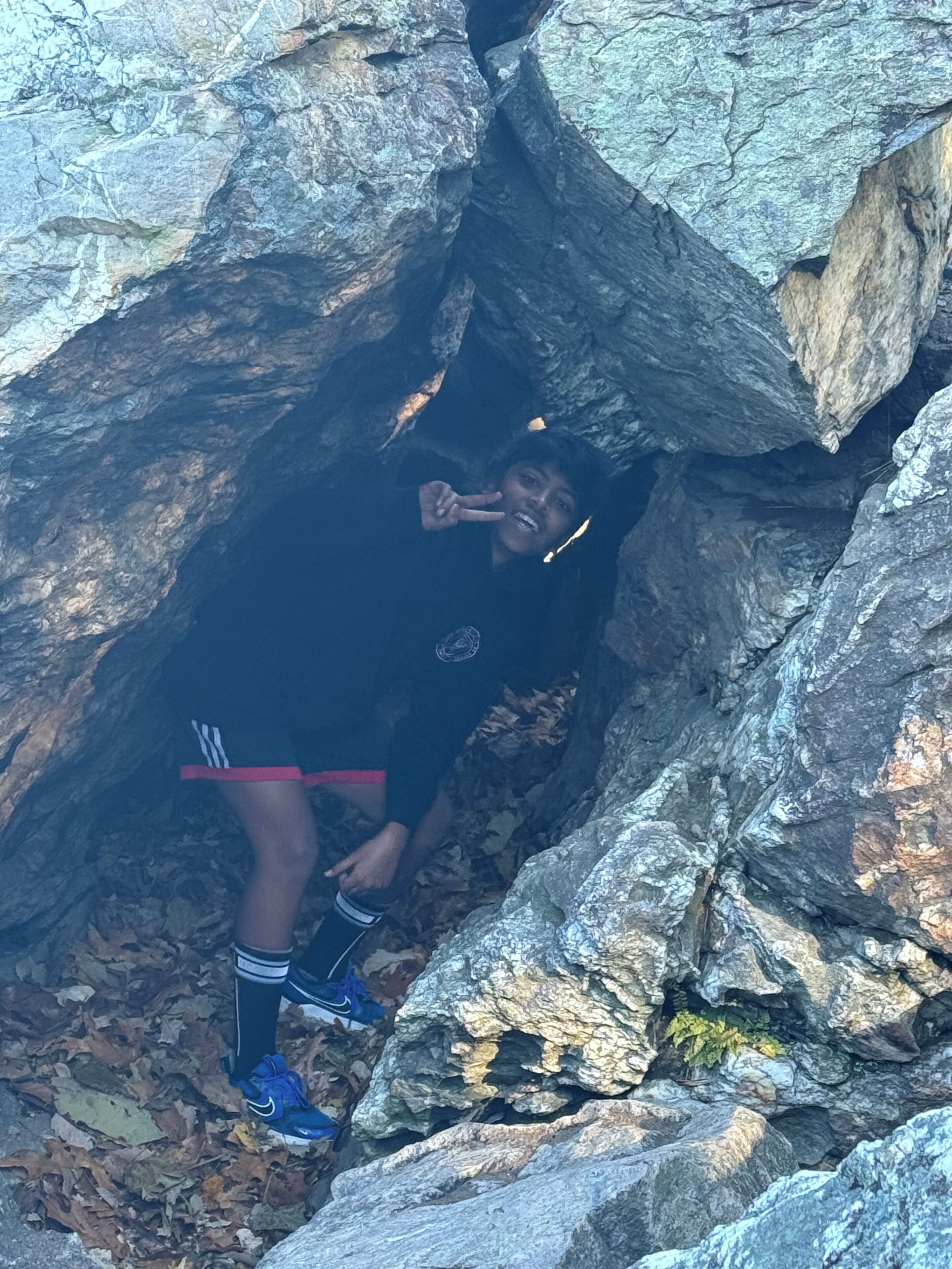 Una persona en una estructura que se asemeja a una cueva, con paredes rocosas y un estrecho pasaje.