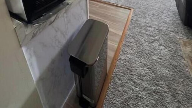 A compact kitchen with a microwave, refrigerator, and dining area with chairs.