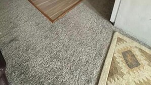 Een kleine keuken met witte kastjes, een magnetron en een koelkast.