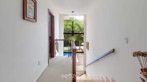 A hallway leading to a balcony with a glass door, a framed picture on the wall, and a ceiling light. - House w/ Pool 180m From Beach in Arraial Pbr0003 (Porto Seguro)