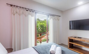 A bedroom with a bed, a TV, a wooden console table, and a balcony with a hammock. - House w/ Pool 180m From Beach in Arraial Pbr0003 (Porto Seguro)