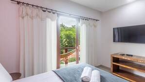 A bedroom with a bed, a TV, a wooden console table, and a balcony with a hammock. - House w/ Pool 180m From Beach in Arraial Pbr0003 (Porto Seguro)
