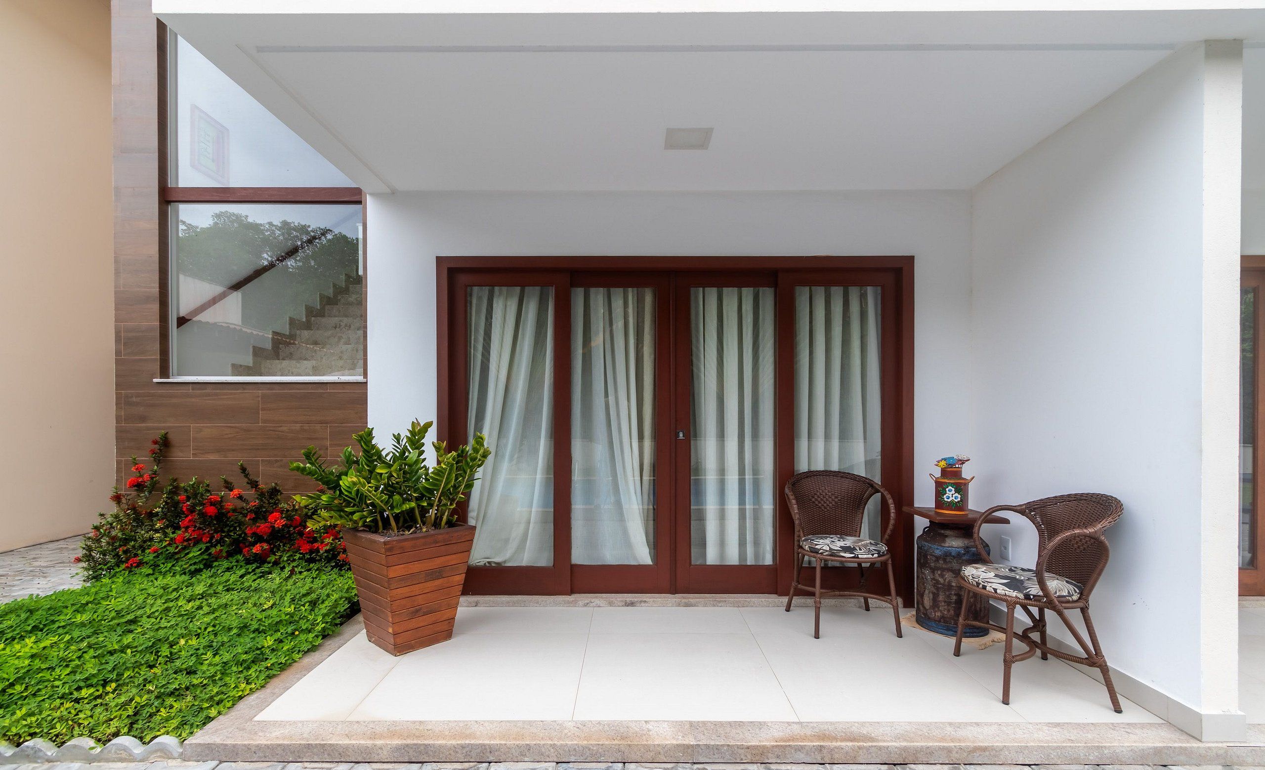 A covered outdoor area with a patio, a seating arrangement, and a staircase leading to an upper level.