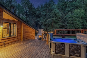 Una cabaña de madera con jacuzzi y chimenea de piedra en una terraza.