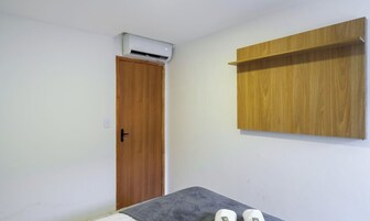 Una habitación con puerta de madera, un equipo de aire acondicionado encima y una repisa de madera en la pared.