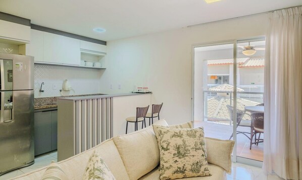 Een moderne keuken met een koelkast, een eethoek met stoelen en een bank met decoratieve kussens.